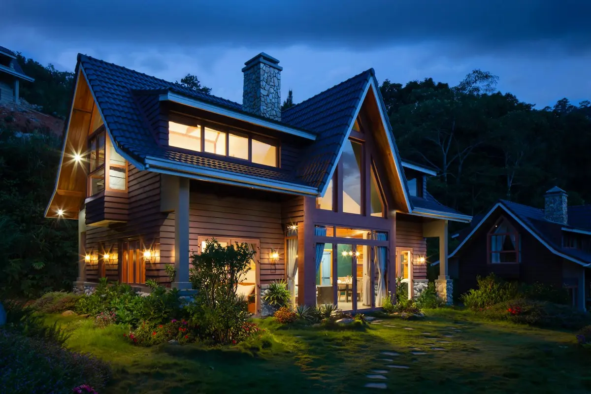 Home with a steep pitched roof at dusk, lit from inside